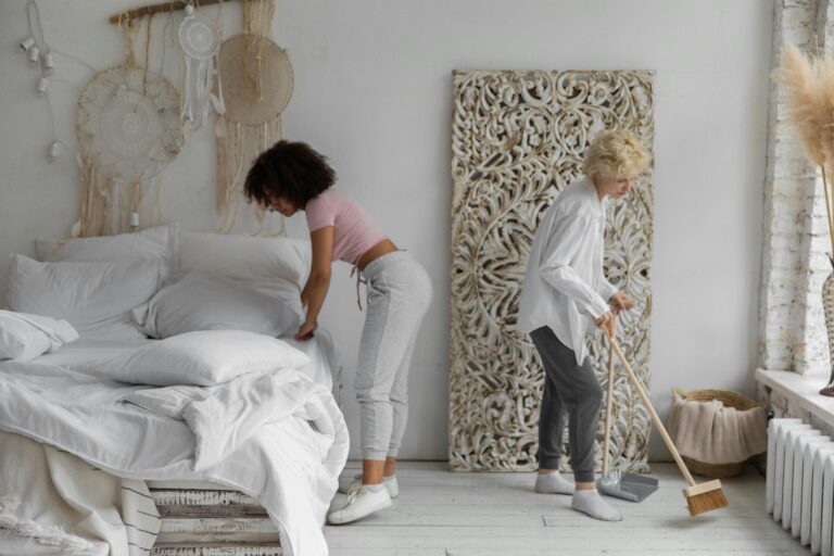 Team of women cleaning bedroom bed broom